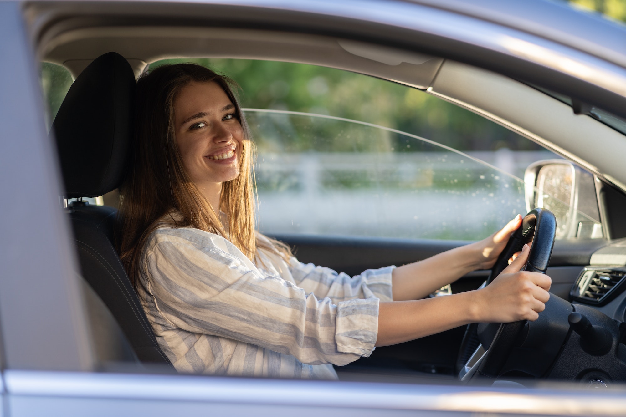Young girl sit at driver seat in new car smiling hold hands on wheel happy to get driver license