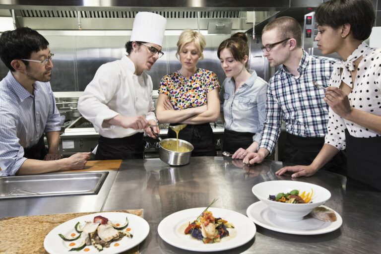 A chef and students at a cookery class in a commercial kitchen