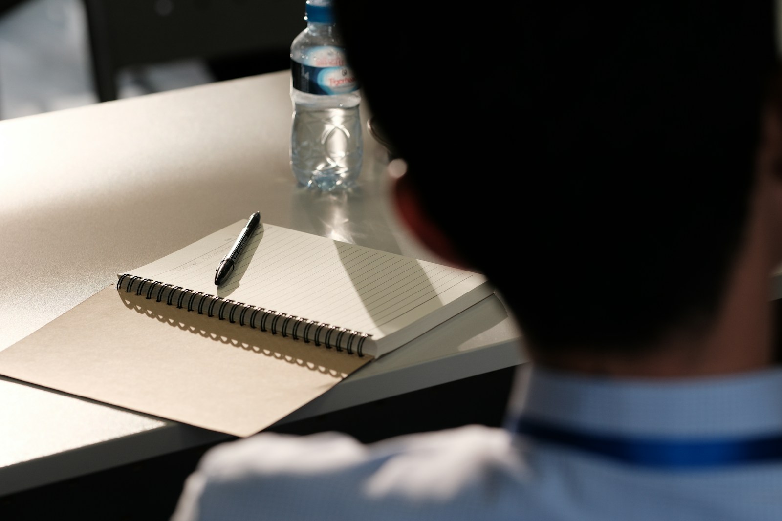 A man sitting at a desk with a notebook and pen